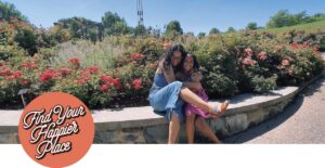Two people sitting on a low wall outdoors, hugging
