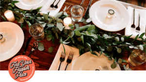 a holiday table set with greenery