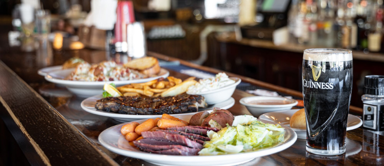 Plates of corned beef and cabbage on an Irish pub bar with a pint of guiness beer