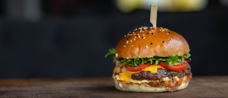 a hamburger on a bun sits against a dark background