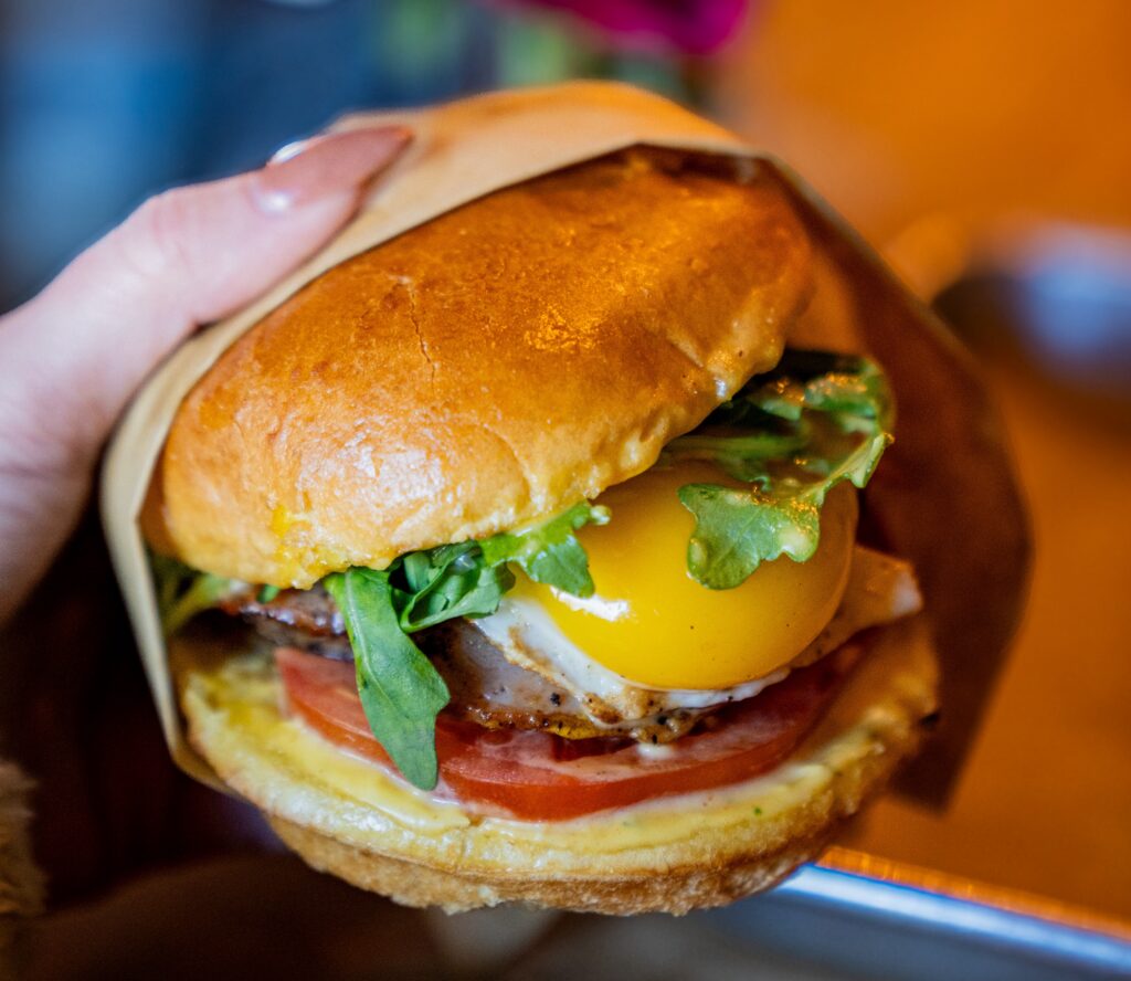 A hamburger with an egg on it in someone's hands