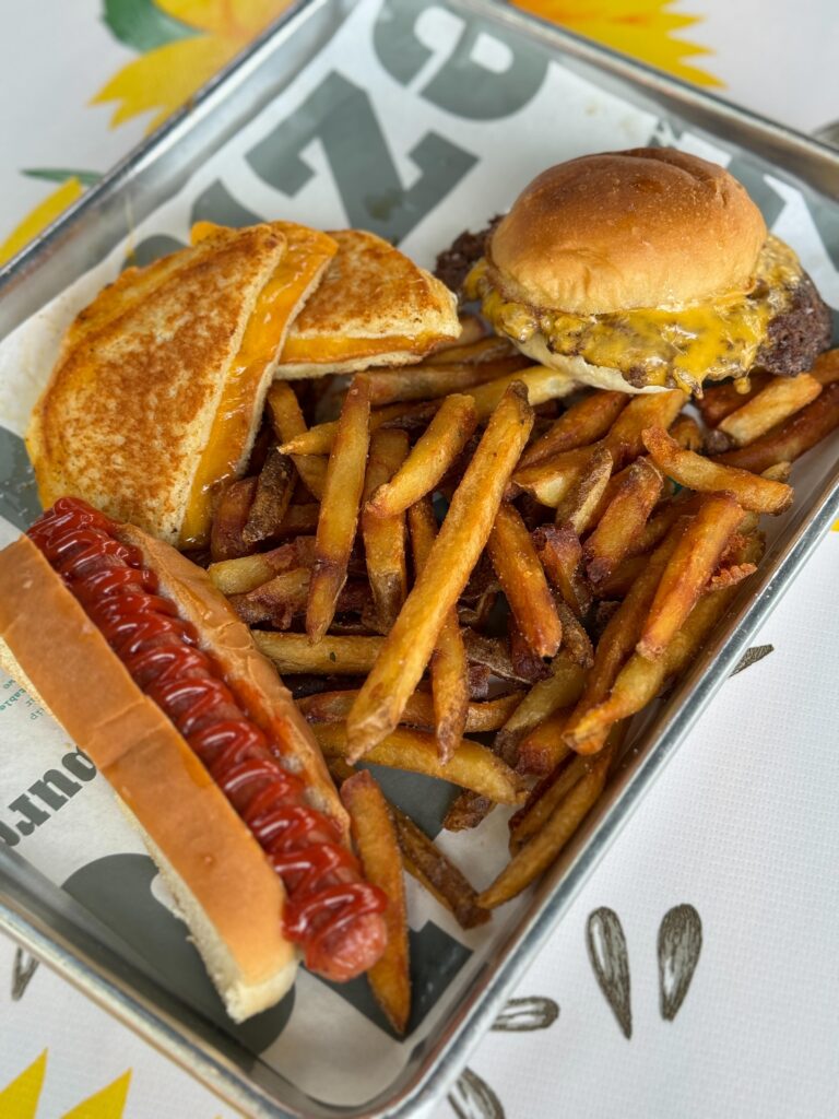 A hamburger, hot dog, and grilled cheese served on a platter with french fries.