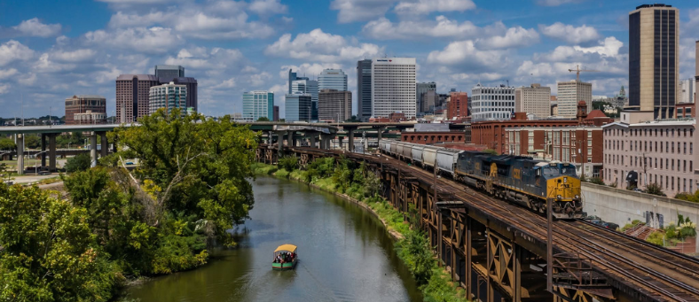 A canal boat cruise heads towards the Richmond skyline along the James River as it merges into the canal
